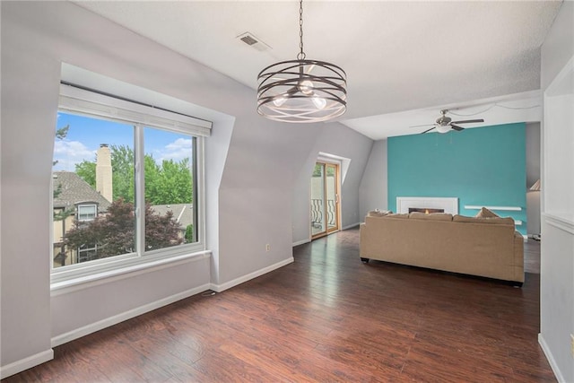 living room featuring baseboards, visible vents, wood finished floors, and ceiling fan with notable chandelier