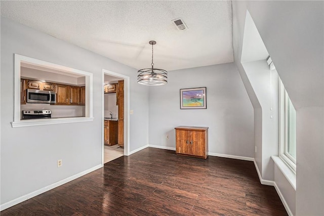 unfurnished dining area featuring visible vents, wood finished floors, baseboards, a textured ceiling, and a notable chandelier