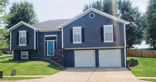 raised ranch featuring concrete driveway, an attached garage, fence, and a front lawn
