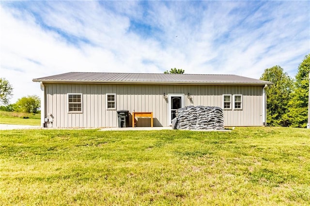 rear view of property with a lawn, board and batten siding, and metal roof