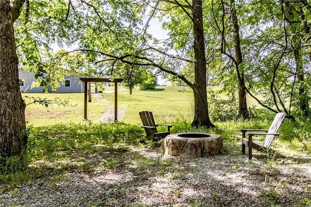 view of green lawn featuring an outdoor fire pit