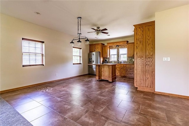 kitchen featuring brown cabinets, baseboards, ceiling fan, and a kitchen island