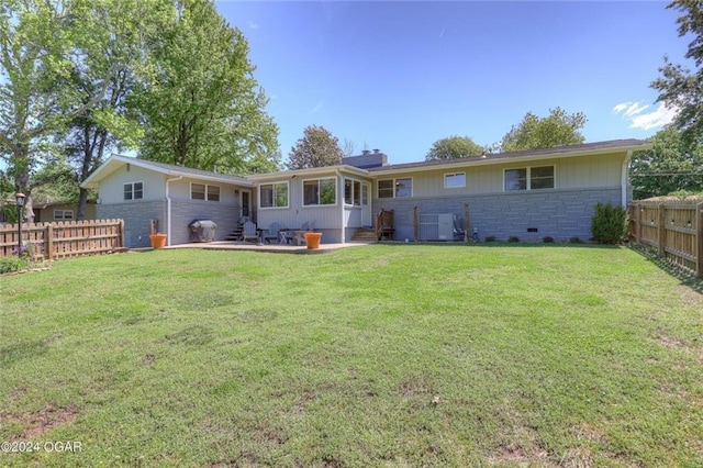 rear view of property featuring a fenced backyard, a yard, stone siding, and entry steps