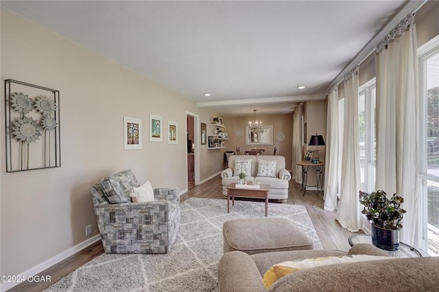 living room featuring recessed lighting, baseboards, an inviting chandelier, and wood finished floors