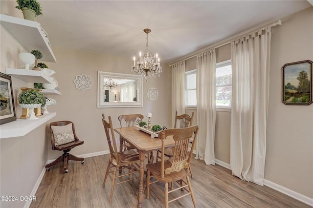 dining area with baseboards, light wood-type flooring, and a chandelier
