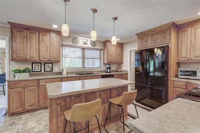 kitchen featuring light countertops, a sink, black appliances, and a kitchen bar