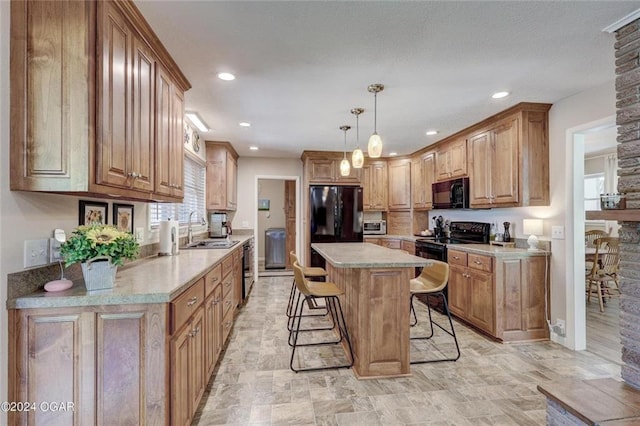 kitchen featuring a kitchen bar, a center island, a sink, light countertops, and black appliances