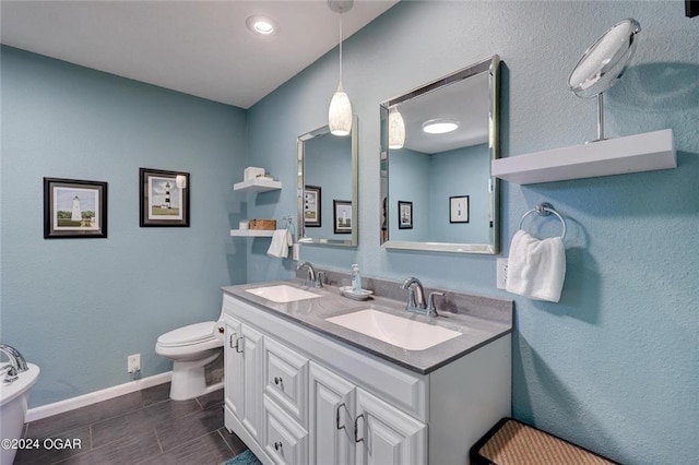 full bathroom featuring baseboards, a sink, double vanity, and toilet