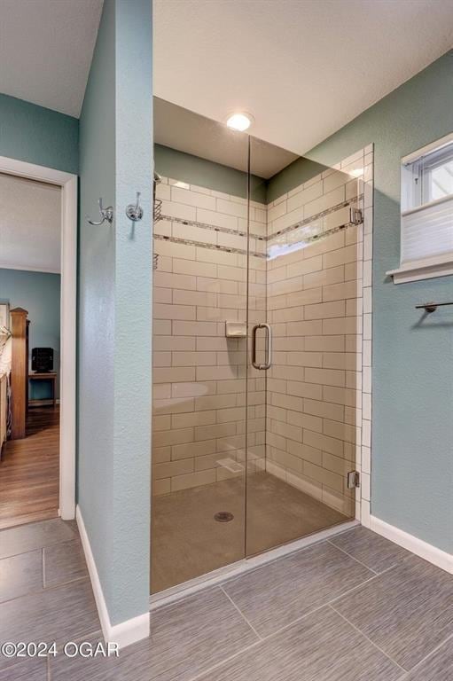 bathroom with baseboards, tile patterned flooring, and a stall shower