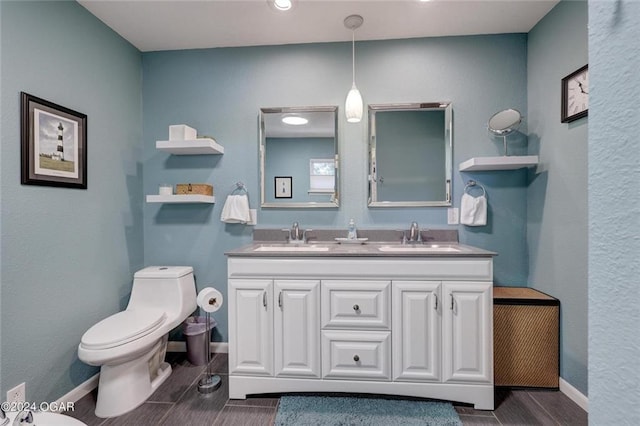full bath with double vanity, toilet, baseboards, and a sink