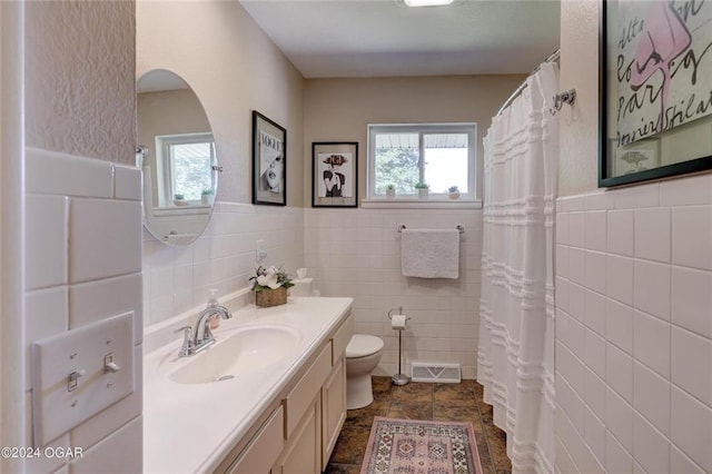 full bathroom featuring wainscoting, vanity, toilet, tile walls, and visible vents