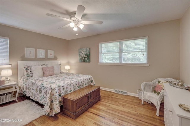 bedroom with a ceiling fan, baseboards, visible vents, and light wood-type flooring