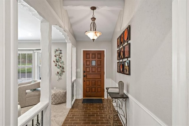 entryway with ornamental molding and brick floor