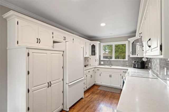 kitchen featuring decorative backsplash, dark wood finished floors, light countertops, white cabinets, and ornamental molding