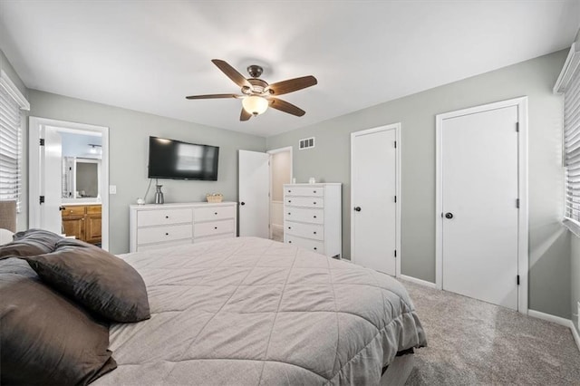 bedroom with visible vents, carpet floors, baseboards, multiple closets, and ensuite bathroom