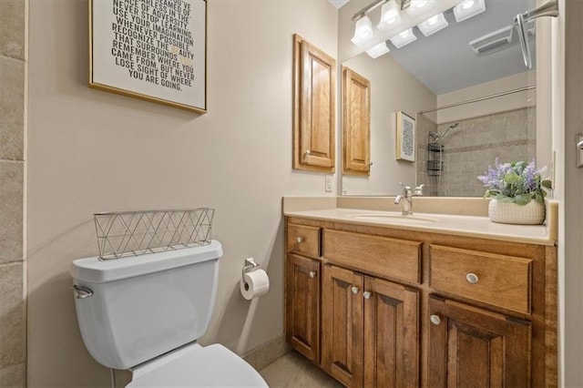 full bath with vanity, a tile shower, and toilet