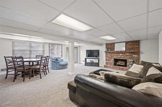 living room featuring carpet floors, a brick fireplace, a drop ceiling, and visible vents