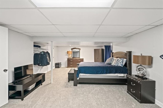 bedroom featuring carpet flooring, baseboards, a drop ceiling, and a closet