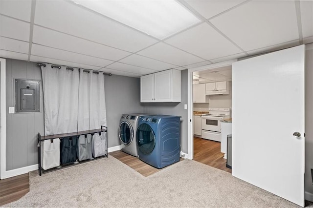 clothes washing area with carpet, baseboards, wood finished floors, washer and clothes dryer, and electric panel