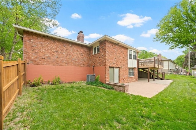back of house with a chimney, a patio area, brick siding, fence, and a yard