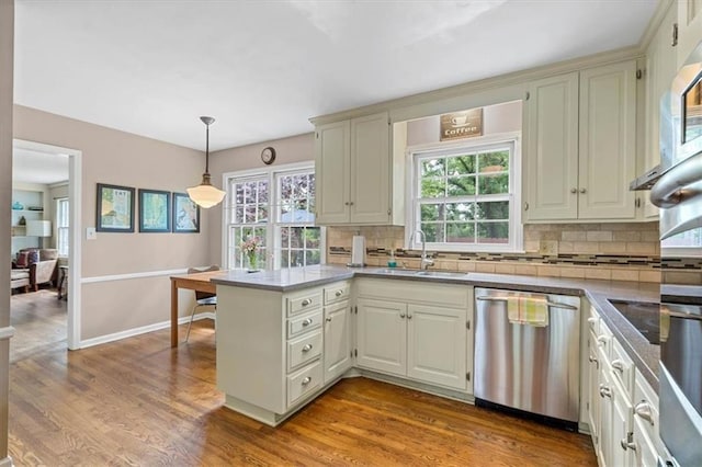 9817 Cedar St, Overland Park, KS 66207 - kitchen with stainless steel dishwasher, a sink, a peninsula, tasteful backsplash, and wood finished floors