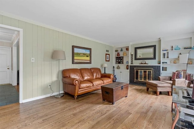 9817 Cedar St, Overland Park, KS 66207 - living area featuring crown molding, light wood-type flooring, a brick fireplace, built in shelves, and baseboards