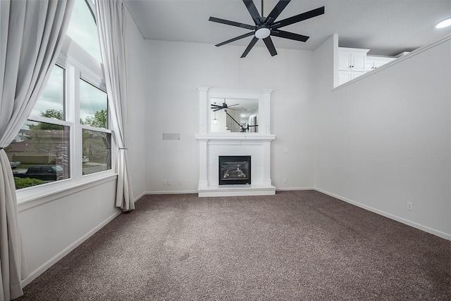 unfurnished living room with carpet floors, baseboards, ceiling fan, and a glass covered fireplace