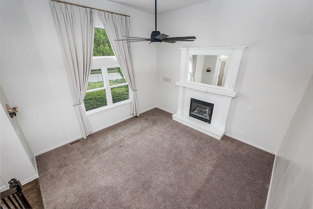 unfurnished living room featuring baseboards, a ceiling fan, carpet, and a glass covered fireplace