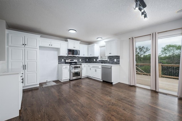 kitchen featuring decorative backsplash, a textured ceiling, appliances with stainless steel finishes, dark wood finished floors, and white cabinetry