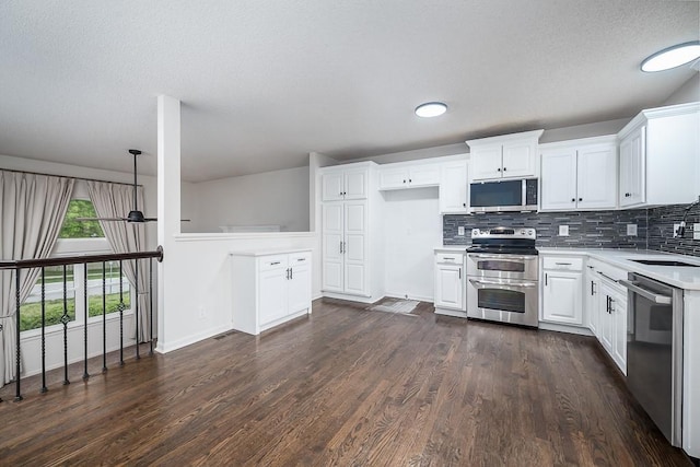 kitchen with appliances with stainless steel finishes, a sink, light countertops, decorative backsplash, and dark wood-style floors