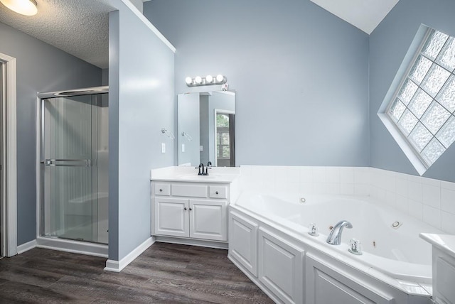 full bathroom featuring vanity, a jetted tub, baseboards, a shower stall, and wood finished floors