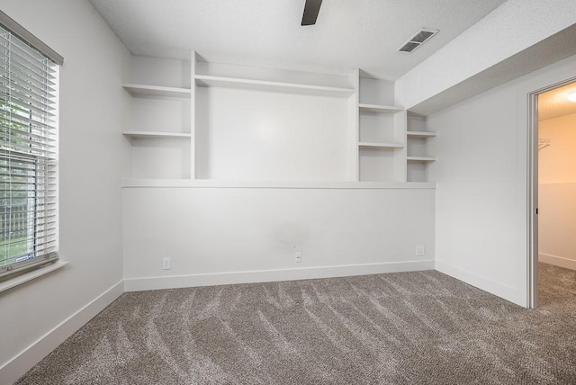 interior space with carpet floors, a ceiling fan, and visible vents