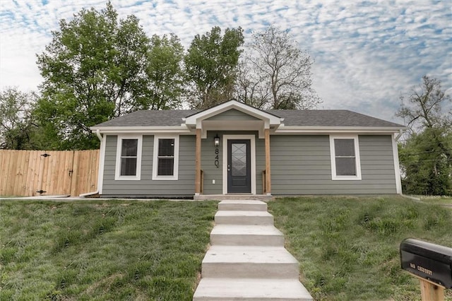 view of front of house with fence, a shingled roof, and a front yard