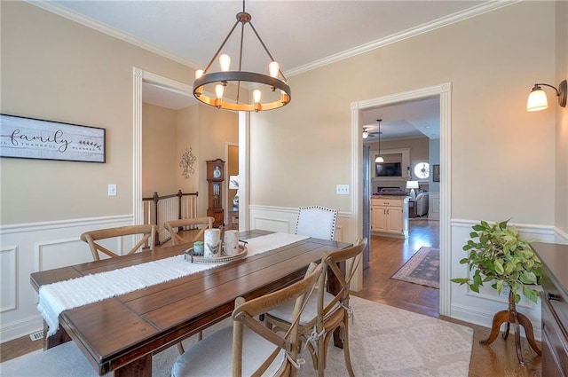 dining area with a notable chandelier, dark wood finished floors, a decorative wall, wainscoting, and ornamental molding