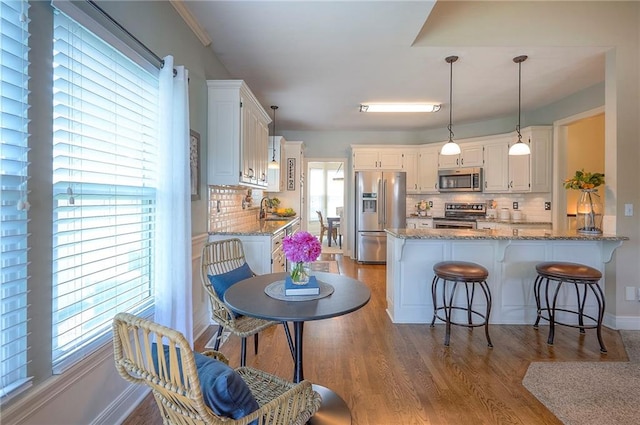 kitchen featuring a peninsula, stainless steel appliances, tasteful backsplash, and wood finished floors