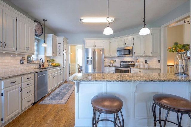 kitchen with white cabinetry, appliances with stainless steel finishes, a kitchen breakfast bar, and a sink