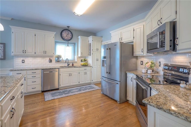 kitchen featuring light wood finished floors, white cabinetry, appliances with stainless steel finishes, and a sink