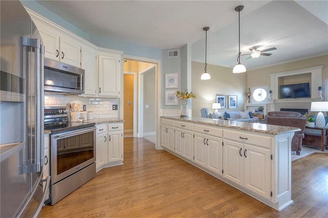 kitchen featuring a peninsula, a ceiling fan, white cabinets, appliances with stainless steel finishes, and tasteful backsplash