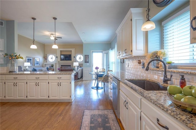 kitchen featuring a sink, light wood finished floors, ornamental molding, and white cabinetry