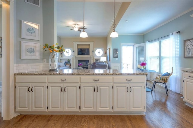 kitchen featuring crown molding, white cabinetry, light wood-type flooring, and visible vents