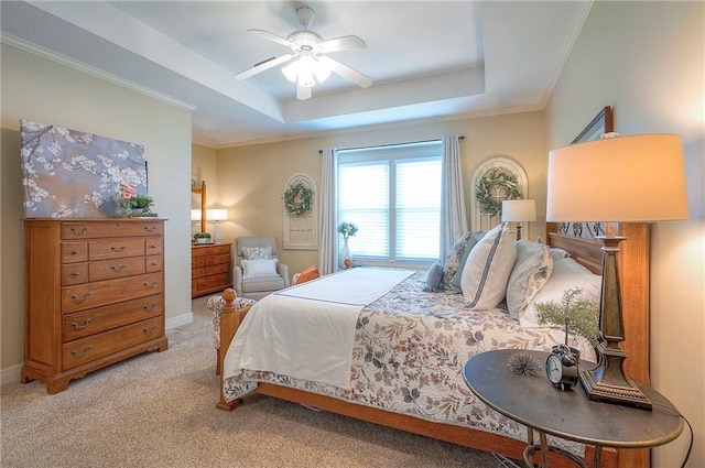 bedroom featuring carpet flooring, a tray ceiling, baseboards, ceiling fan, and ornamental molding
