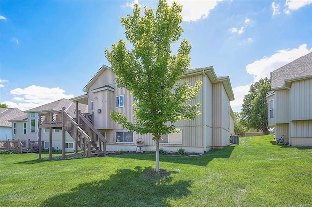 rear view of house featuring a yard, a wooden deck, cooling unit, and stairway