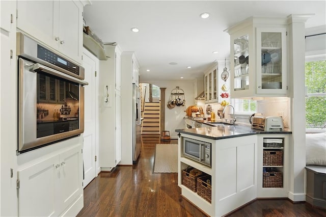 6116 W 61st Ter, Mission, KS 66202 - kitchen featuring appliances with stainless steel finishes, dark wood finished floors, dark countertops, glass insert cabinets, and a peninsula
