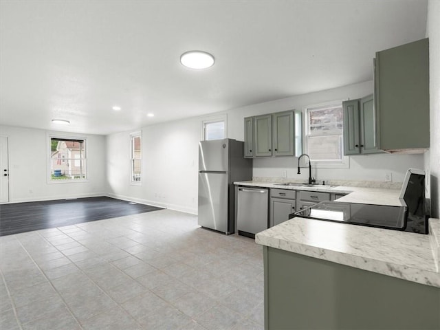 kitchen featuring baseboards, light countertops, gray cabinets, a sink, and stainless steel appliances