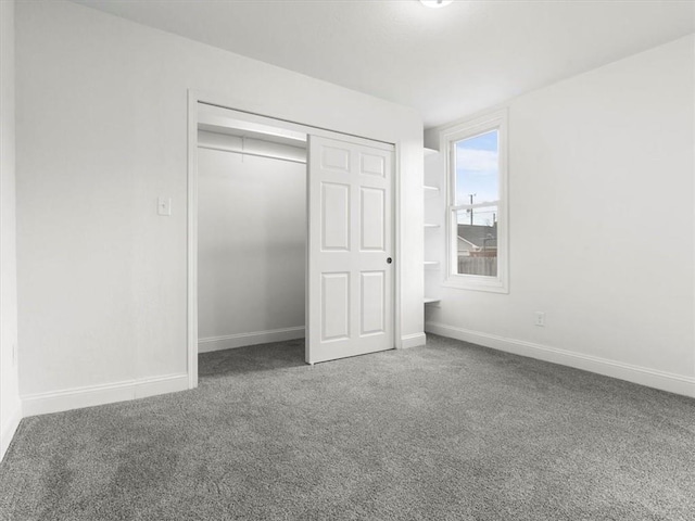 unfurnished bedroom with baseboards, carpet flooring, and a closet