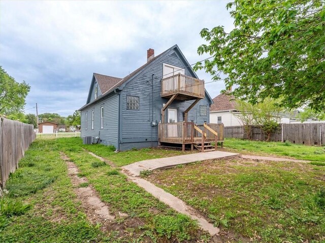 back of property with a wooden deck, a balcony, cooling unit, a fenced backyard, and a chimney