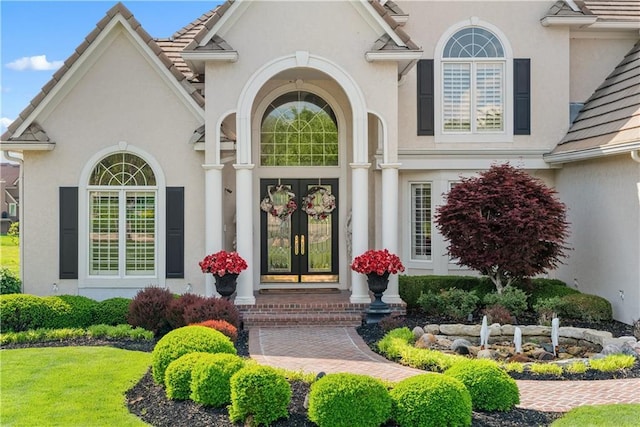 property entrance with stucco siding and french doors
