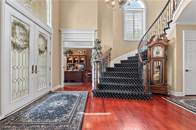 foyer featuring a chandelier, wood finished floors, baseboards, and stairs