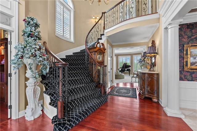 entrance foyer featuring stairway, wood finished floors, a wainscoted wall, and decorative columns