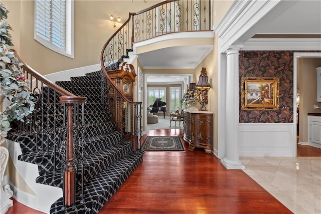 entryway featuring ornamental molding, wainscoting, decorative columns, stairs, and wood finished floors